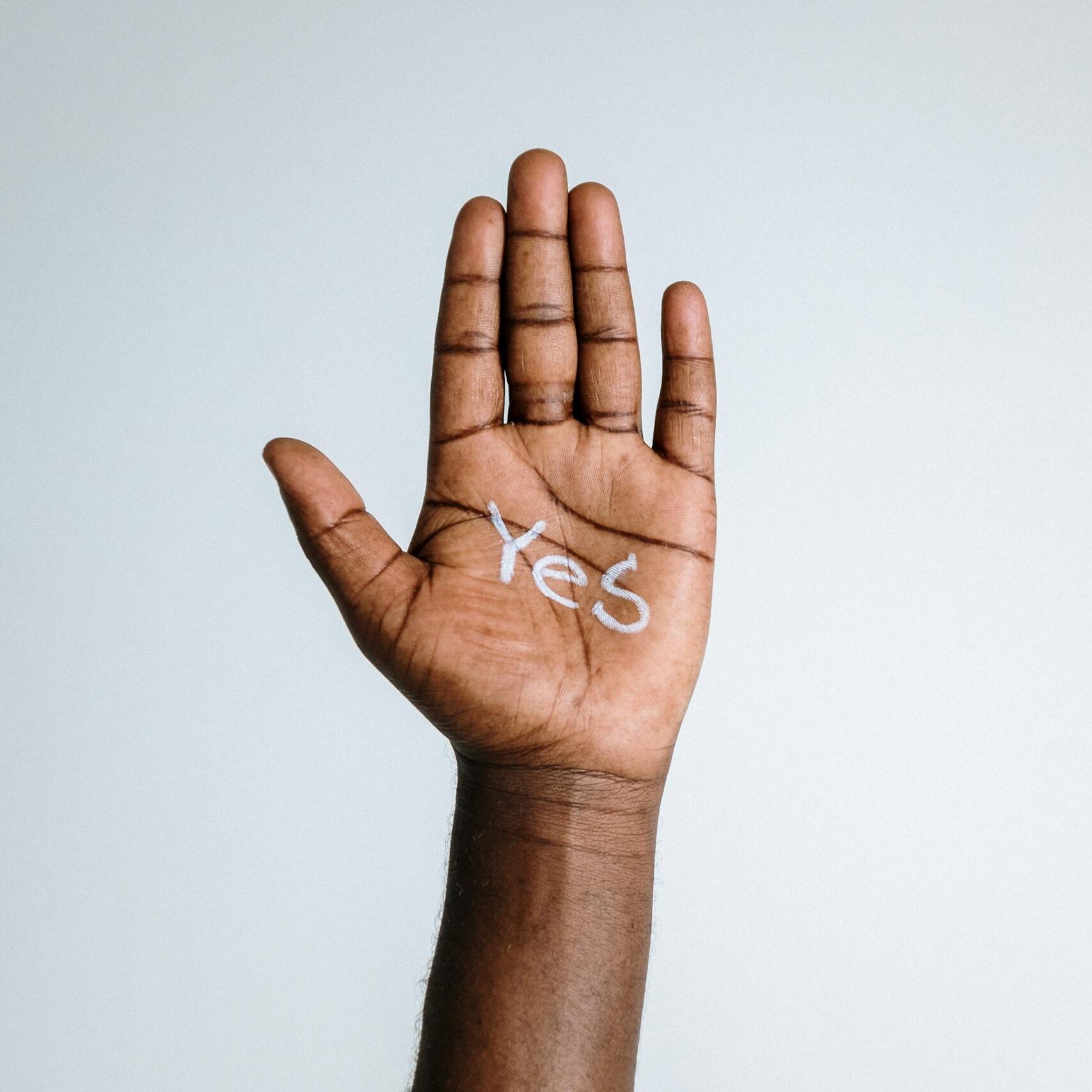 Close-up of a raised hand with 'Yes' written on the palm, symbolizing agreement and positivity.